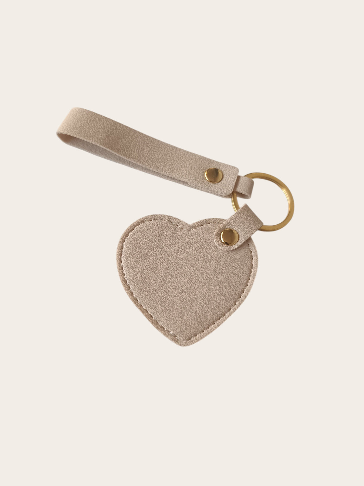 Campus Zone beige vegan leather heart-shaped keychain with a wristlet strap and polished gold-tone hardware.