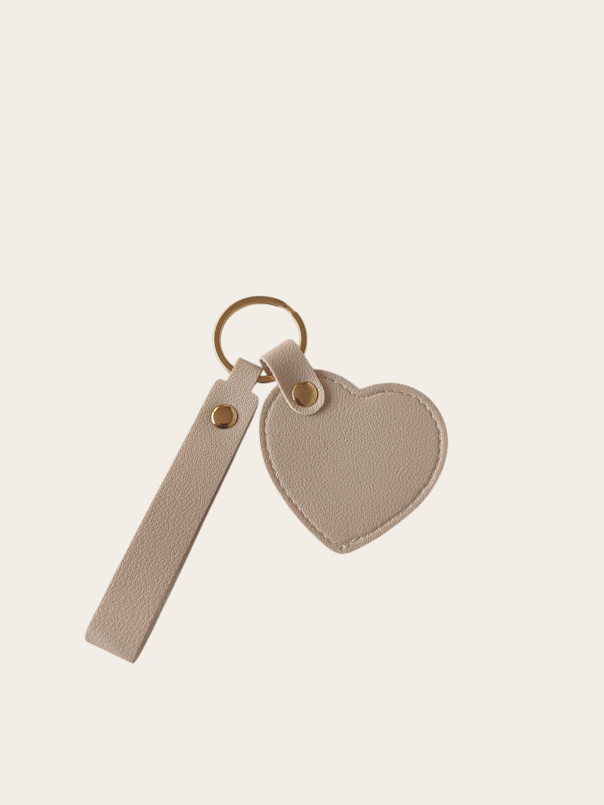 Campus Zone beige vegan leather heart-shaped keychain with a wristlet strap and polished gold-tone hardware.